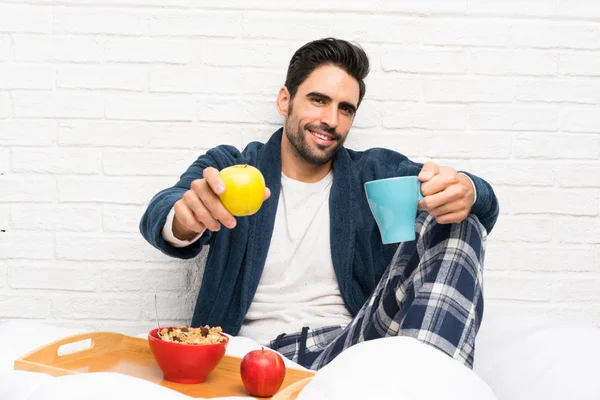 Man in bed with dressing gown and having breakfast