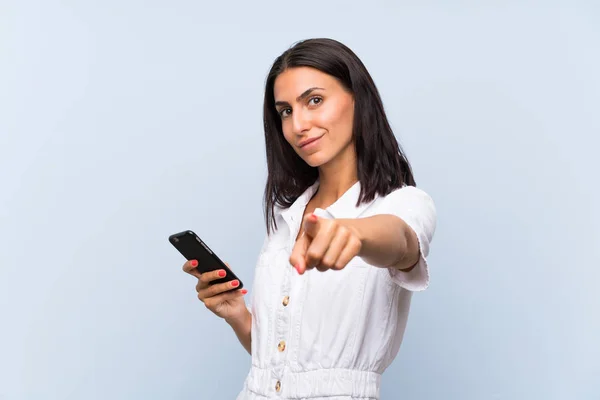 Junge Frau Mit Handy Über Isolierter Blauer Wand Zeigt Mit — Stockfoto