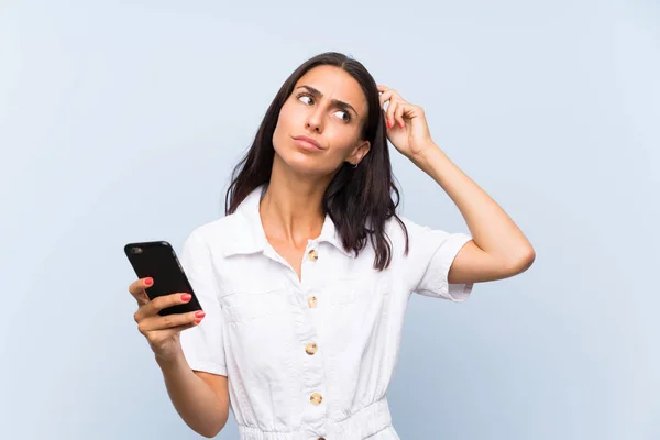 Young Woman Mobile Phone Isolated Blue Wall Having Doubts Confuse — Stock Photo, Image