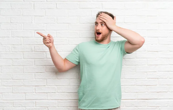 Blonde Man Brick Wall Surprised Pointing Finger Side — Stock Photo, Image