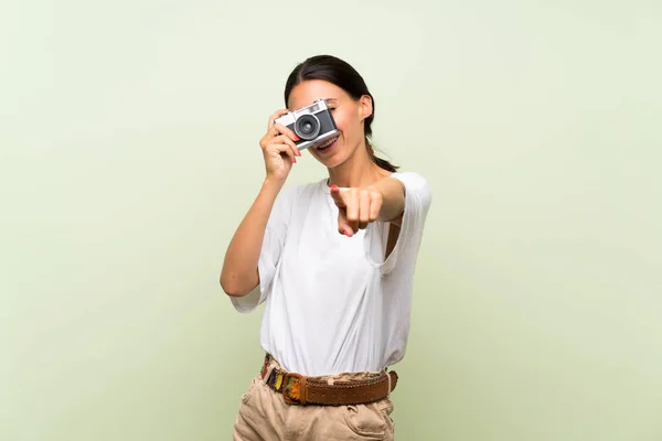 年轻女子在孤立的绿色背景拿着相机 — 图库照片