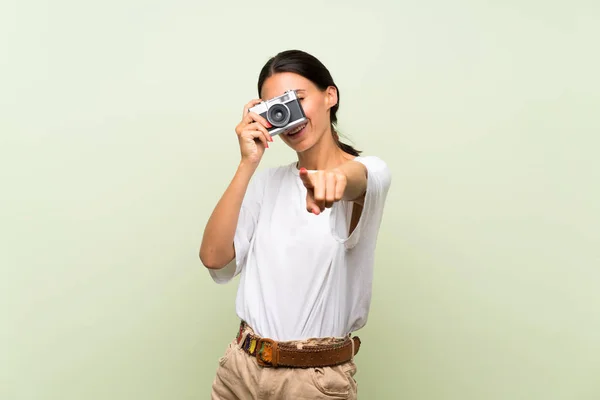 Mujer Joven Sobre Fondo Verde Aislado Sosteniendo Una Cámara —  Fotos de Stock