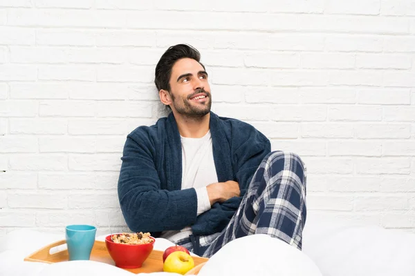 Hombre Cama Con Bata Desayunando Mirando Hacia Arriba Mientras Sonríe —  Fotos de Stock