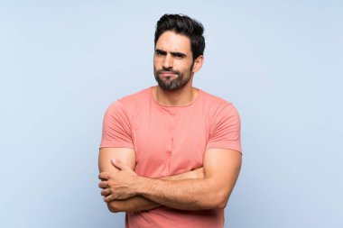 Izole mavi arka plan üzerinde pembe gömlek yakışıklı genç adam üzgün duygu