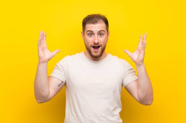 Sürpriz yüz ifadesi ile sarı arka plan üzerinde yakışıklı adam