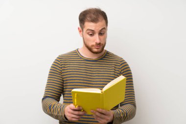 Izole beyaz duvar üzerinde Yakışıklı adam tutan ve bir kitap okuma