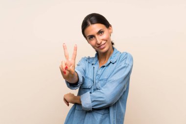 Arka planda kalmış genç bir kadın gülümsüyor ve zafer işareti gösteriyor.