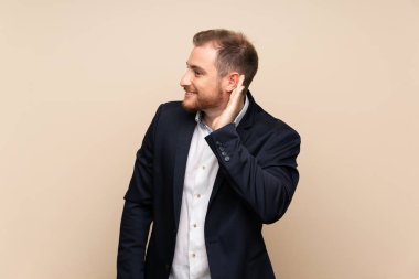 Izole arka plan üzerinde Sarışın adam kulak elini koyarak bir şey dinlerken