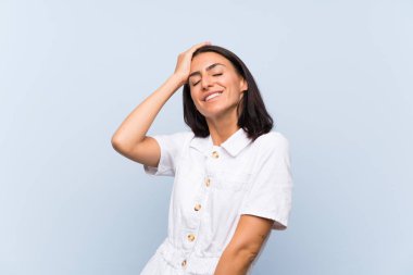 Genç bir kadın mavi arka planda gülüyor.