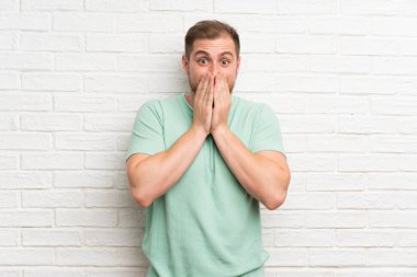 Sürpriz yüz ifadesi ile tuğla duvar üzerinde sarışın adam