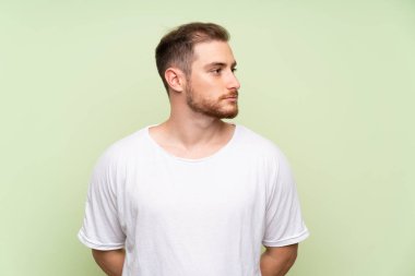 Yeşil arka plan üzerinde yakışıklı adam yan görünümlü
