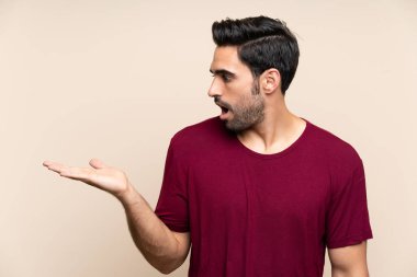 Avuç üzerinde copyspace hayali tutan izole arka plan üzerinde Yakışıklı genç adam