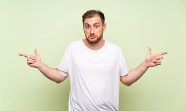 Yeşil arka plan üzerinde yakışıklı adam şüpheleri olan laterals işaret