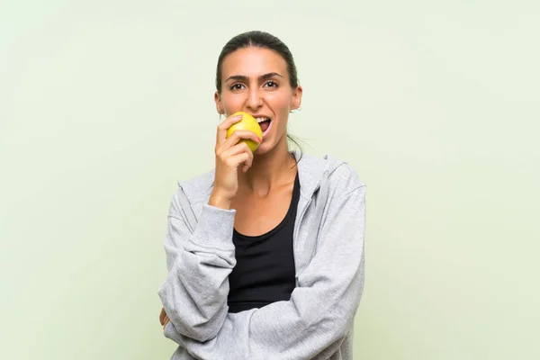 Jonge Sportvrouw Met Een Appel Geïsoleerde Groene Achtergrond — Stockfoto