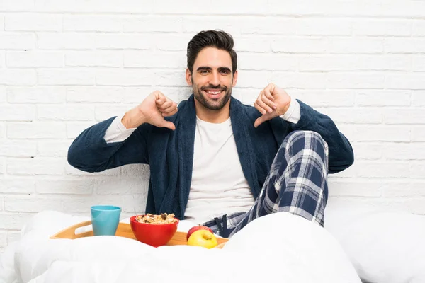 Man in bed with dressing gown and having breakfast proud and self-satisfied
