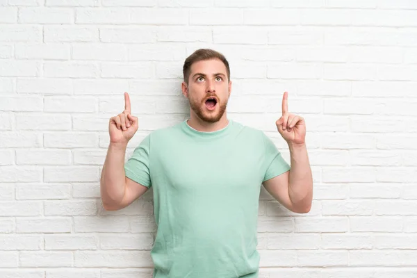 Blonde Man Brick Wall Pointing Index Finger Great Idea — Stock Photo, Image