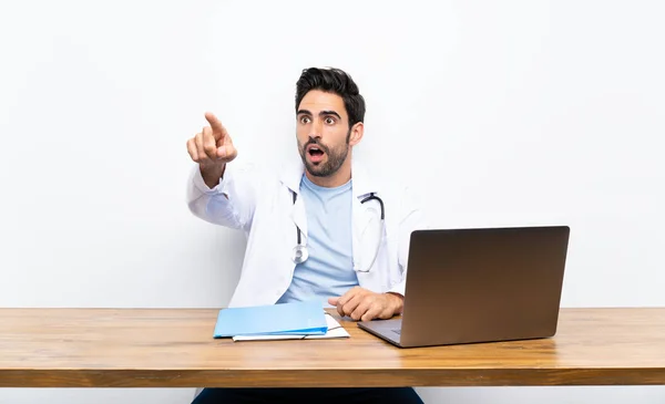 Jovem Médico Homem Com Seu Laptop Sobre Parede Isolada Apontando — Fotografia de Stock