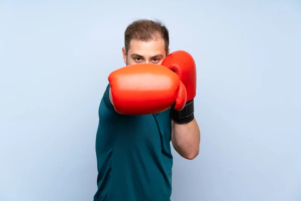 Blonde sport man over blue wall with boxing gloves — Stock Photo, Image