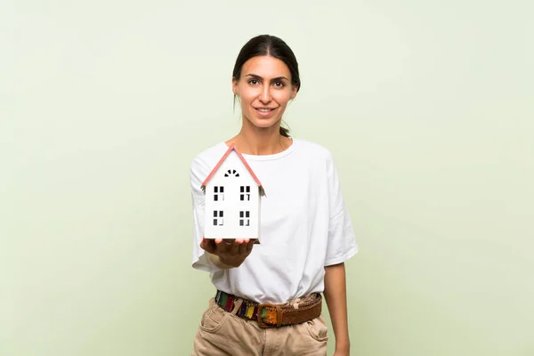 Jovem Mulher Sobre Isolado Fundo Verde Segurando Uma Pequena Casa — Fotografia de Stock