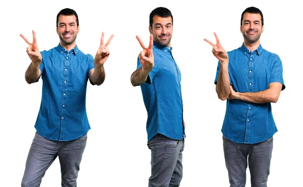 Conjunto de homem bonito com camisa azul sorrindo e mostrando vitória — Fotografia de Stock