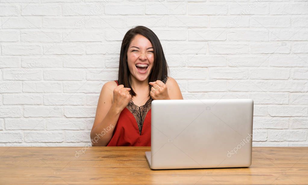 Young Mexican woman with a laptop celebrating a victory