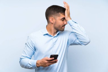 Izole mavi duvar üzerinde cep ile genç yakışıklı adam bir şey fark etti ve çözüm niyetinde