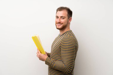 Izole beyaz duvar üzerinde Yakışıklı adam tutan ve bir kitap okuma