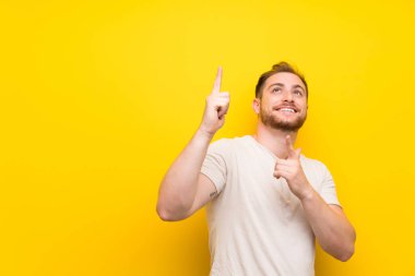 Sarı arka plan üzerinde yakışıklı adam Dizin parmağı ile işaret büyük bir fikir