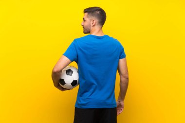 Izole sarı duvar üzerinde genç yakışıklı futbolcu adam