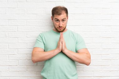 Tuğla duvar üzerinde Blonde adam yalvarıyor