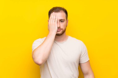 Elle bir göz kapsayan sarı arka plan üzerinde Yakışıklı adam