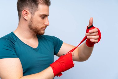 Boks bandaj mavi duvar üzerinde sarışın spor adam