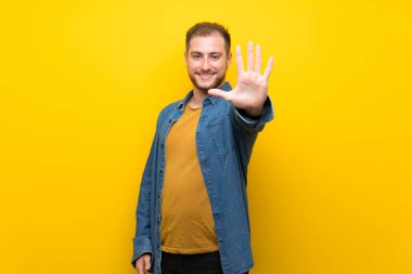 Izole sarı duvar üzerinde Sarışın adam parmakları ile beş sayma