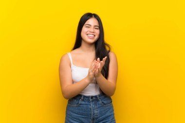 Bir konferansta sunum dan sonra alkışlayan izole sarı arka plan üzerinde Genç genç Asyalı kız