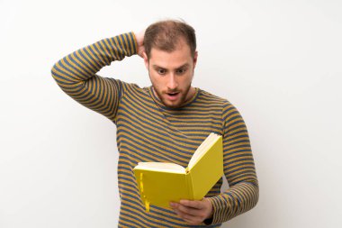 Izole beyaz duvar üzerinde Yakışıklı adam tutan ve bir kitap okuma