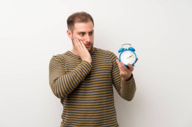 Vintage çalar saat tutan izole beyaz duvar üzerinde Yakışıklı adam