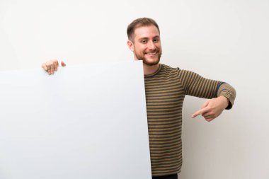İzole beyaz duvar üzerinde yakışıklı adam eklemek için boş bir beyaz plasard tutan bir kavram