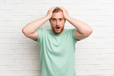 Sürpriz yüz ifadesi ile tuğla duvar üzerinde sarışın adam