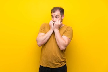 Izole sarı duvar sinirli üzerinde Sarışın adam ve ağızellerini koyarak korkmuş