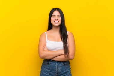 Izole sarı arka plan üzerinde genç genç Asyalı kız kollarını ön konumda geçti tutmak