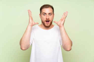 Sürpriz yüz ifadesi ile yeşil arka plan üzerinde yakışıklı adam