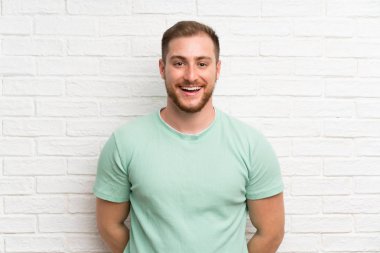 Sürpriz yüz ifadesi ile tuğla duvar üzerinde sarışın adam