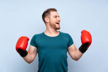 Boks eldiven ile mavi duvar üzerinde sarışın spor adam