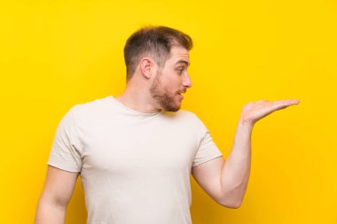 Avuç içinde copyspace hayali tutan sarı arka plan üzerinde Yakışıklı adam