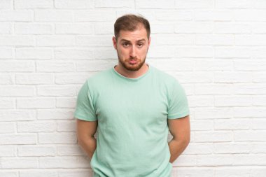 Tuğla duvar üzgün üzerinde Blonde adam