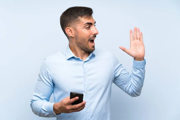 Junger Gutaussehender Mann Mit Handy Über Isolierter Blauer Wand Der — Stockfoto