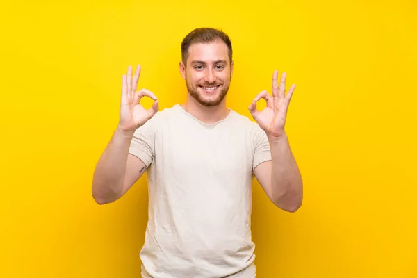 Przystojny Człowiek Żółtym Tle Pokazując Znak Palcami — Zdjęcie stockowe