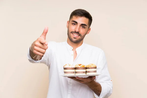 Knappe Man Houdt Muffin Cake Geïsoleerde Achtergrond Met Duimen Omhoog — Stockfoto