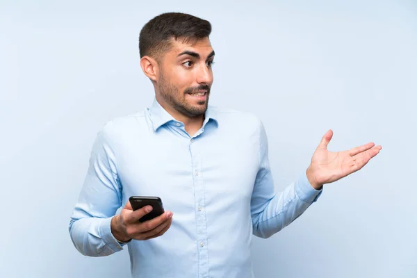 Junger Gutaussehender Mann Mit Handy Über Isolierter Blauer Wand Mit — Stockfoto