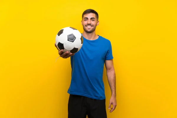 Giovane giocatore di calcio bello uomo oltre isolato muro giallo — Foto Stock